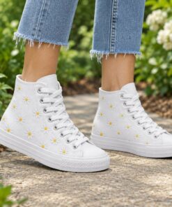 Woman wearing white high-top canvas sneakers with daisy embroidery on a sunny park path, cropped from the knees down