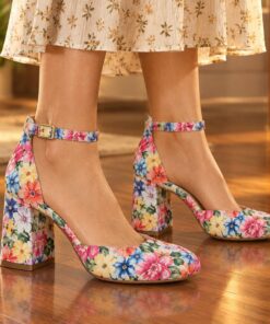 Woman wearing floral print ankle strap pumps with 2.5 inch block heel at an evening party, cropped from the knees down