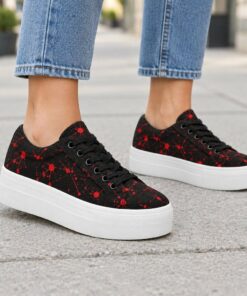 Woman wearing black and red paint splatter low-top platform sneakers on a city sidewalk, cropped from the knees down