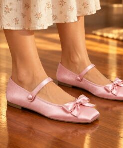 Woman wearing pink satin square toe Mary Jane flats with bow at an evening party, cropped from the knees down