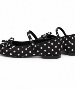 Pair of women's black and white polka dot Mary Jane flats standing, side profile and back heel view