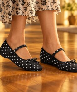 Woman wearing black and white polka dot Mary Jane flats at an evening party, cropped from the knees down