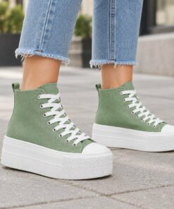 Woman wearing sage green high-top platform canvas sneakers on a city sidewalk, cropped from the knees down