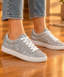 Woman wearing silver glitter low-top sneakers at an evening party, cropped from the knees down
