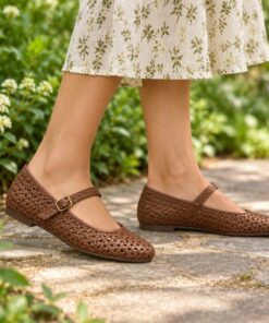 Woman wearing brown woven vegan leather Mary Jane flats on a sunny park path, cropped from the knees down